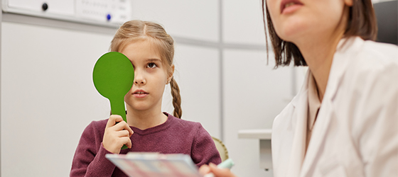 Little Girl Reading Eye Chart at Vision Test